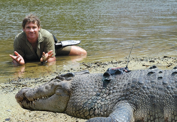 Steve Irwin laying in the water with crocodile in front of him.