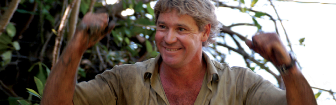 Steve Irwin with fists raised above his head and smiling.